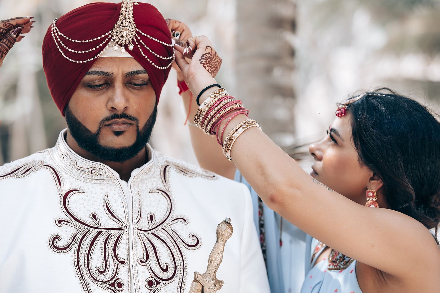 Traditional wedding ceremony under palm trees with decorative elements and cultural attire.