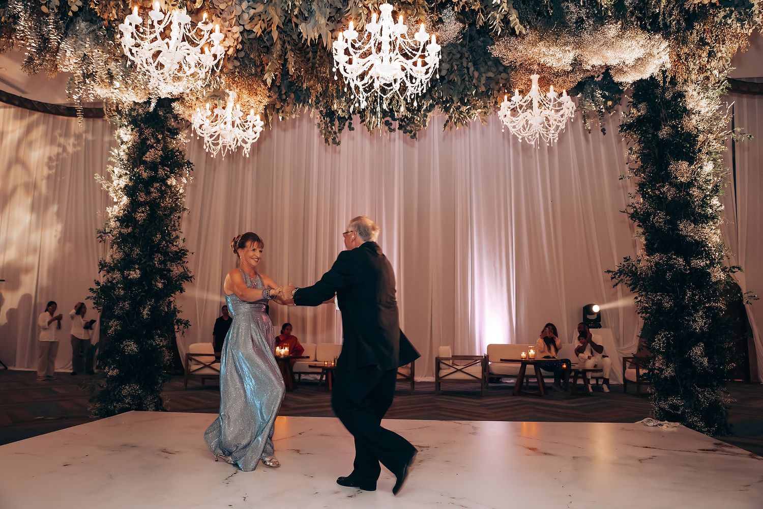 Wedding celebration in an elegant ballroom decorated with floral arches and soft lighting.