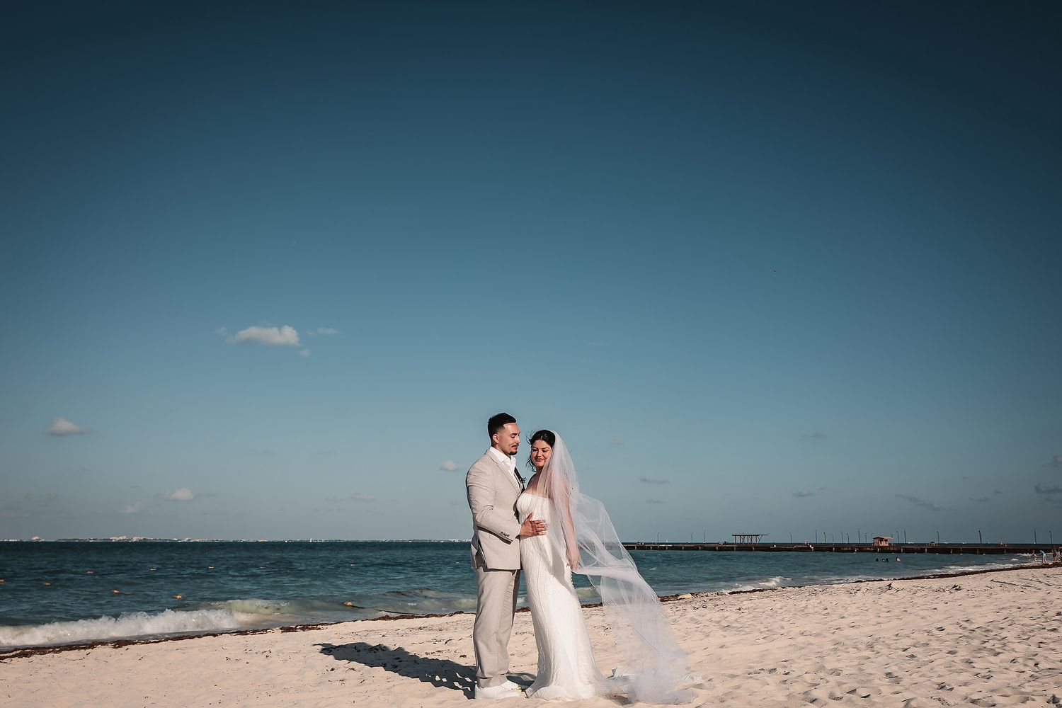 Romantic beach wedding portraits with crystal blue ocean waters in the background.