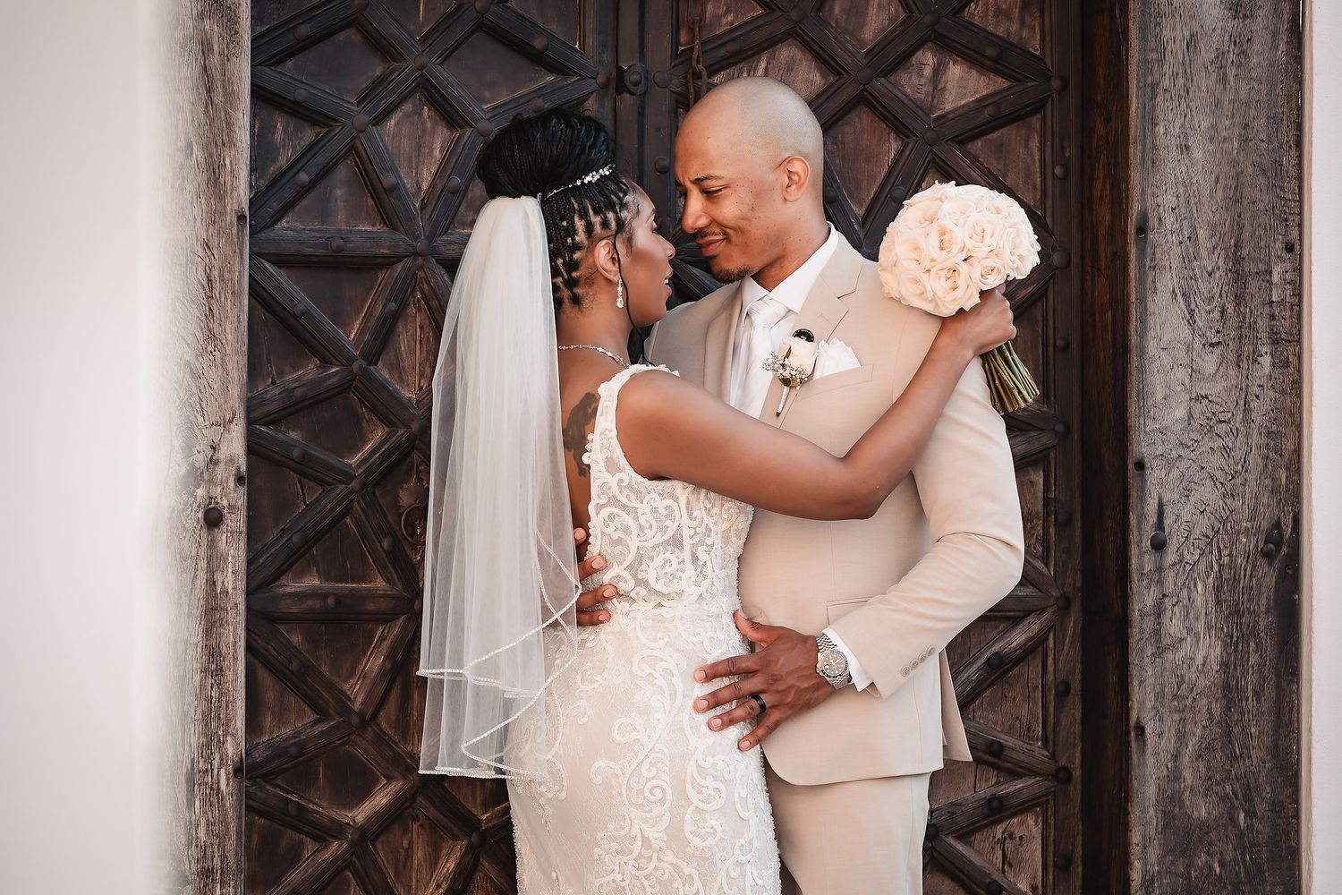 A romantic moment captured between newlyweds in front of an ornate wooden door.