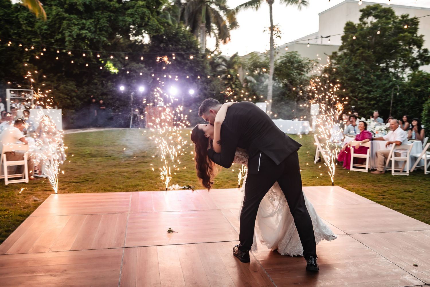 Dramatic wedding dance dip with sparklers creating magical light effects outdoors.