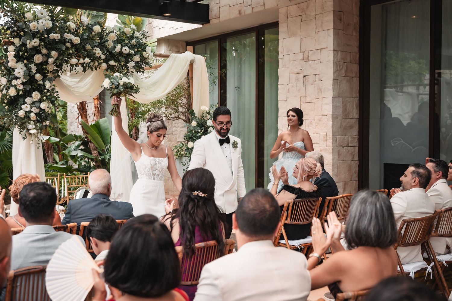Wedding celebration moment with guests applauding under an outdoor pergola.
