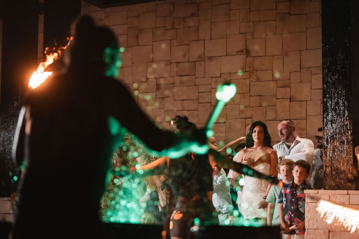 Wedding celebration with sparklers creating a magical nighttime display against stone wall backdrop.