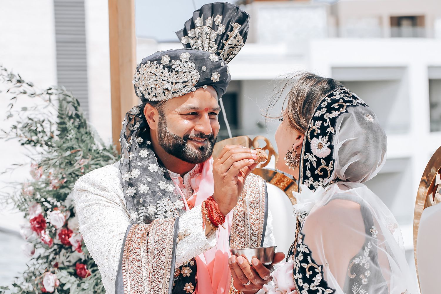 A couple in traditional South Asian wedding outfits exchanging joyful glances during their celebration.