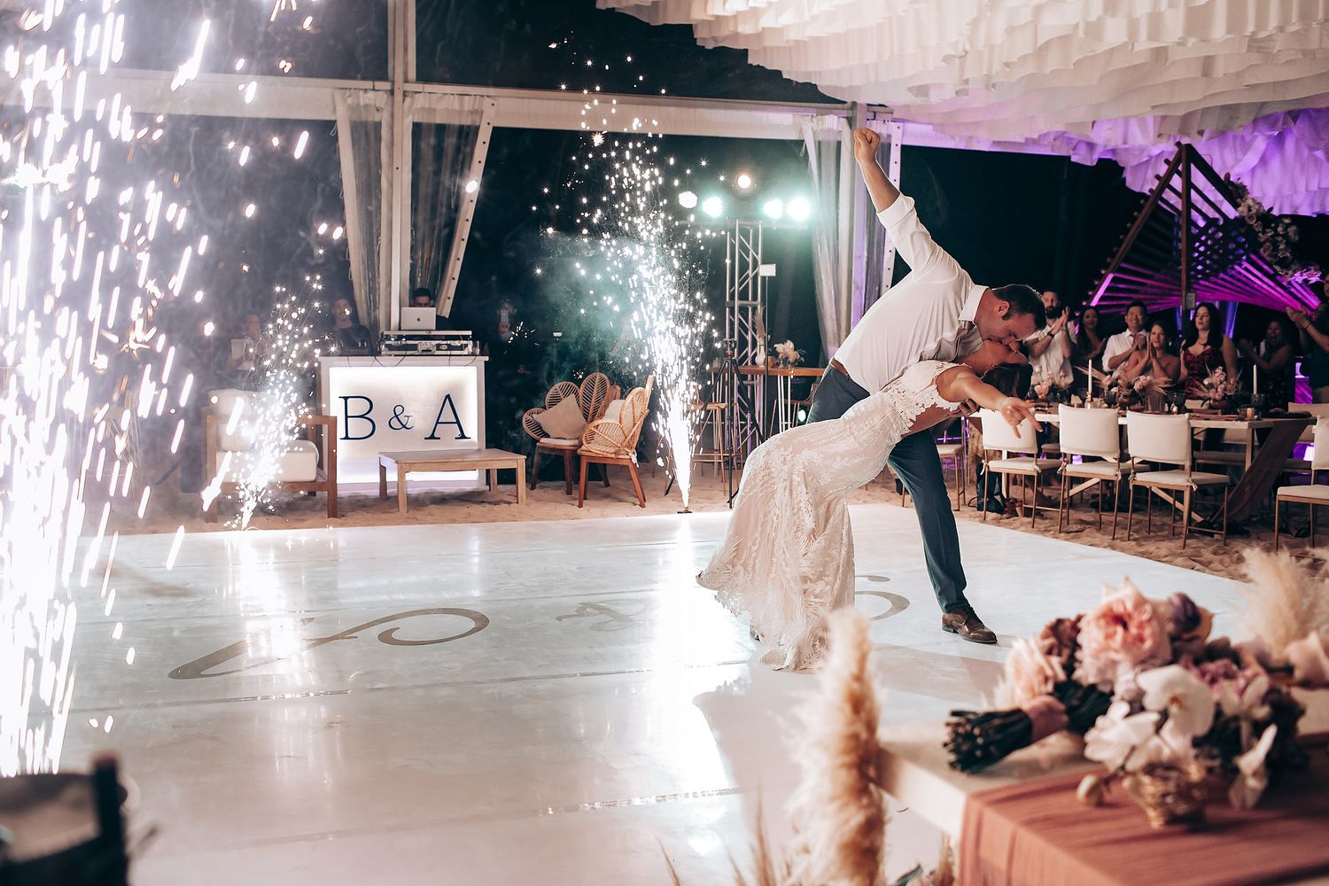 Ice skaters perform in a winter show with sparkling pyrotechnics illuminating the dark arena stage.