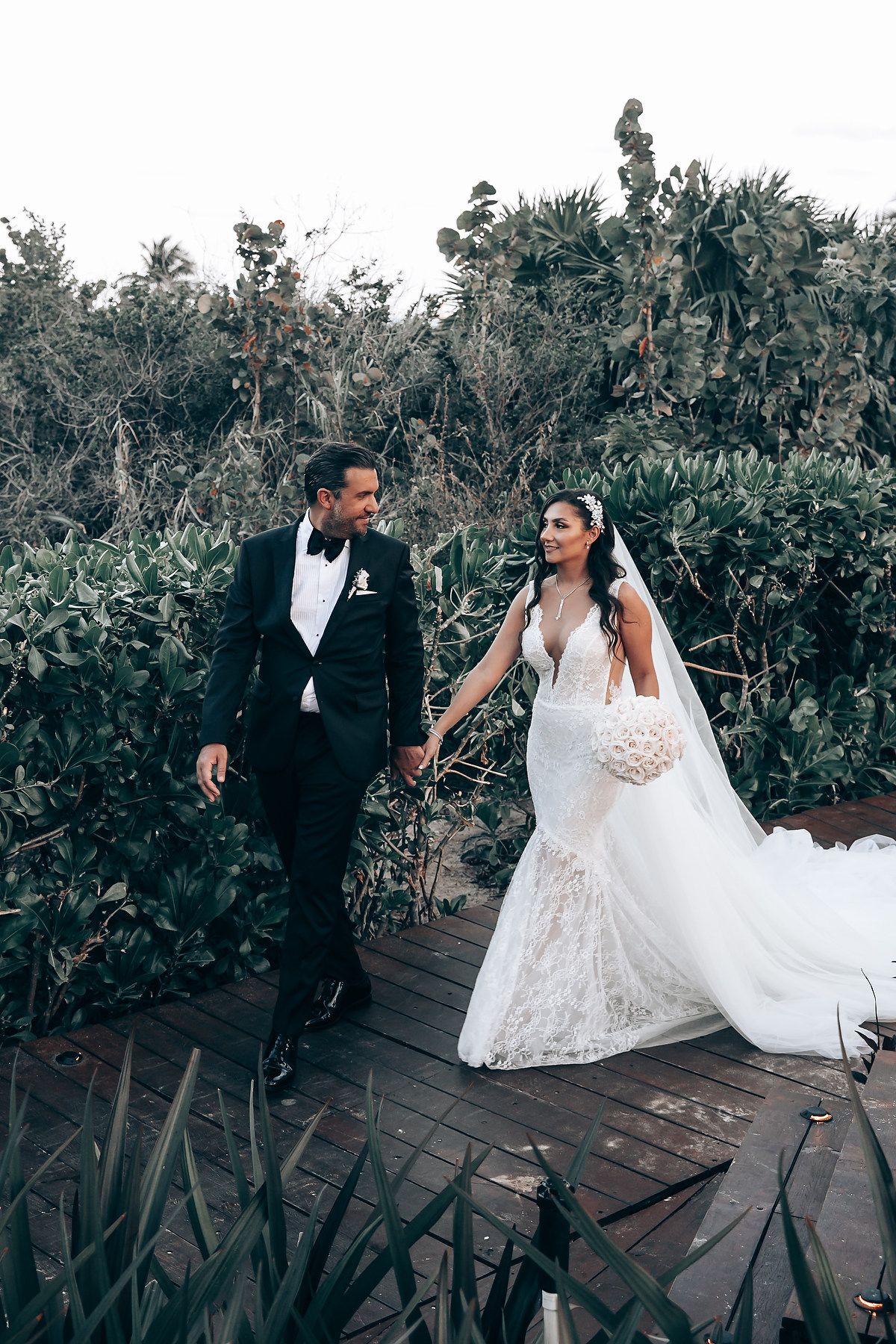 A romantic wedding photoshoot on a wooden deck surrounded by tropical greenery and ocean views.