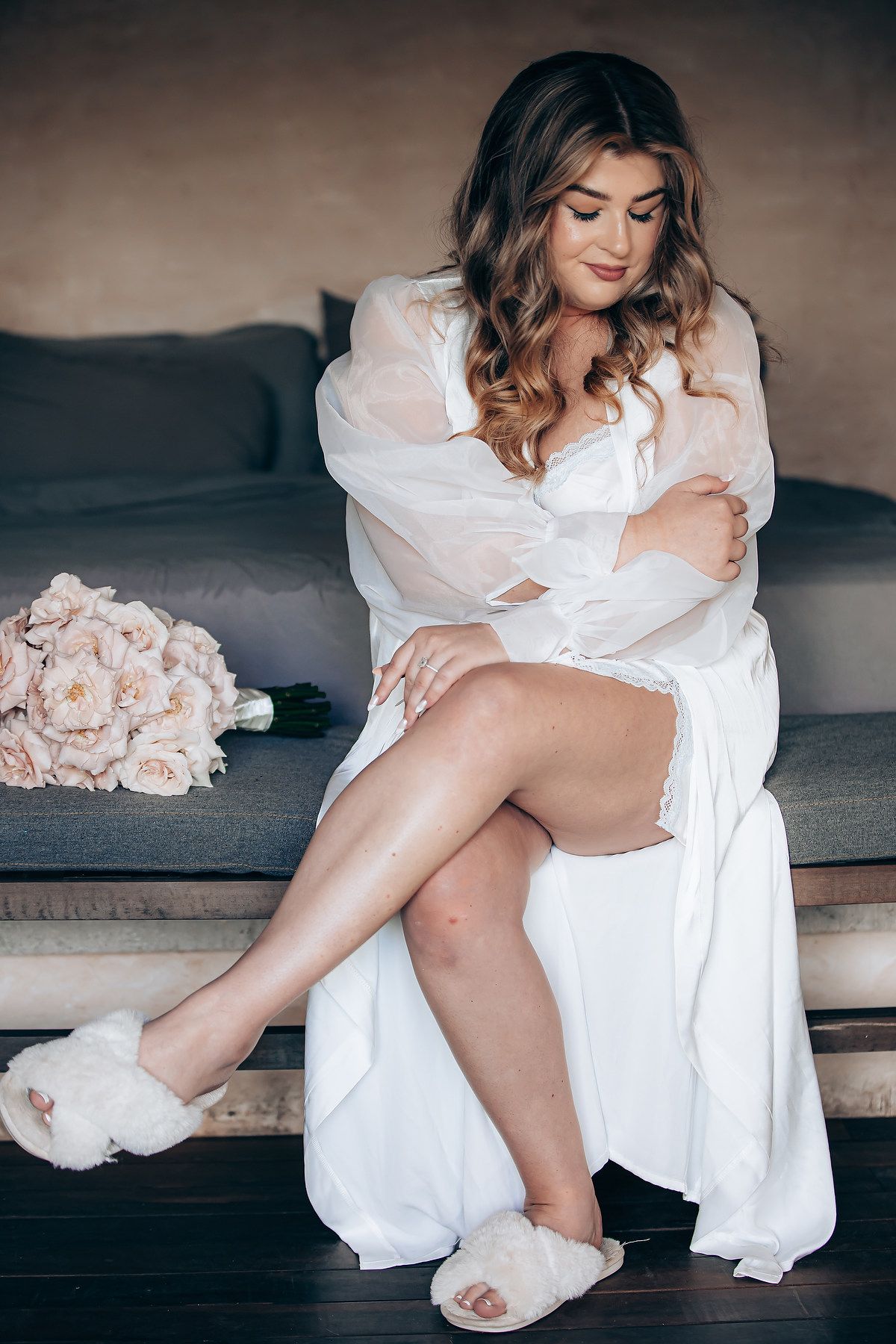 Artistic bridal boudoir photo with pink roses and white silk robe.