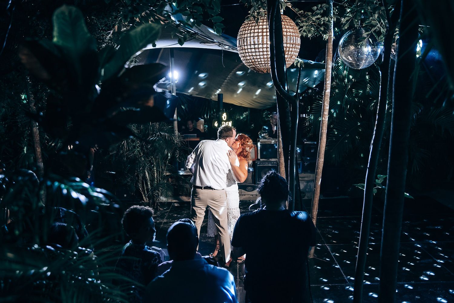 Wedding reception dance floor illuminated with dramatic spotlights and disco effects.