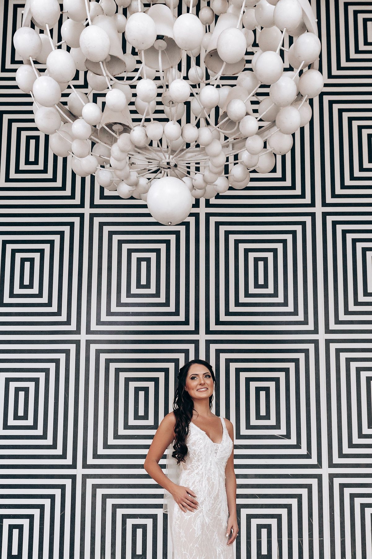 Modern geometric black and white wall with hanging white globe lights creates a striking pattern.