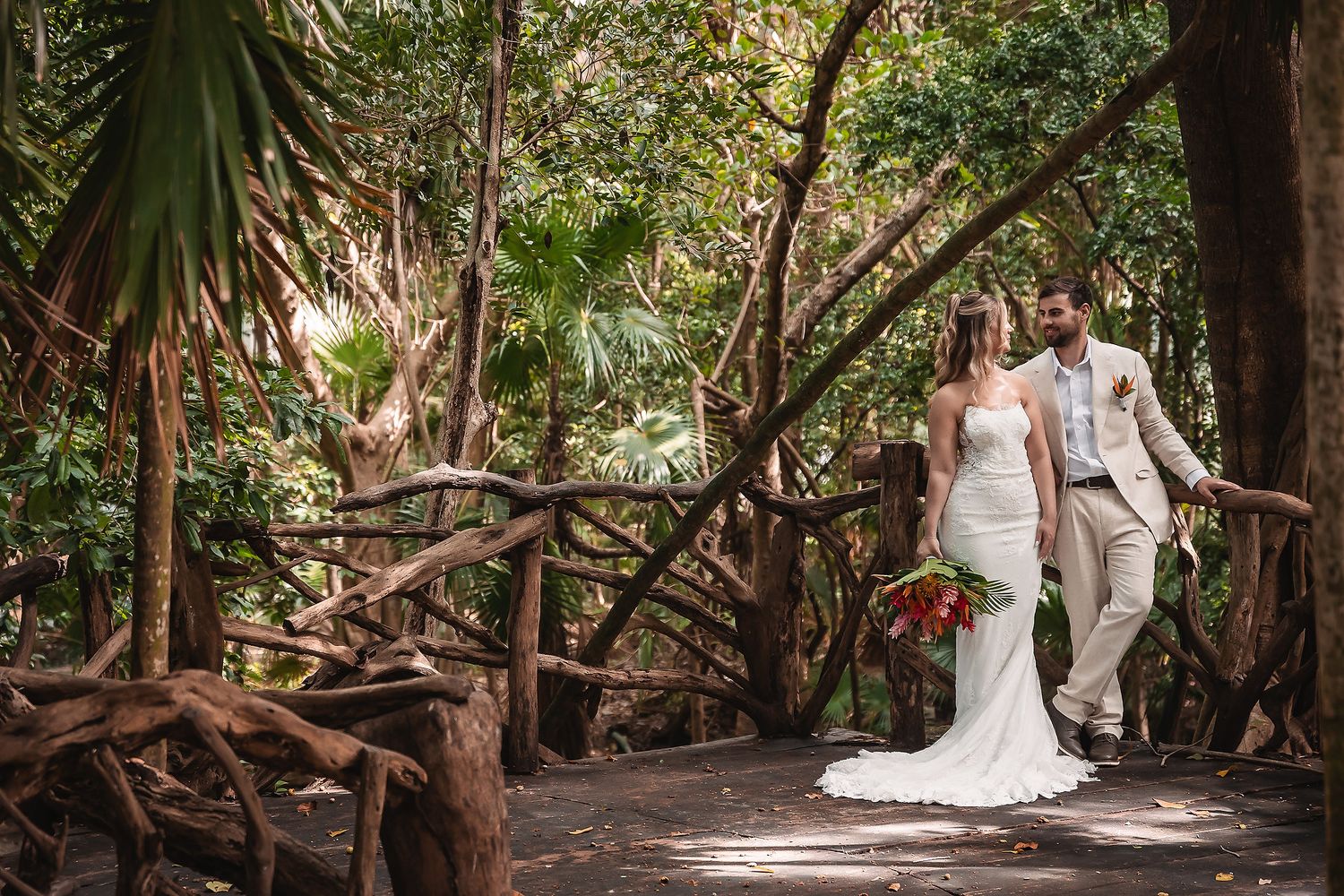Tropical wedding ceremony setup with lush greenery and palm trees along a natural stone pathway.