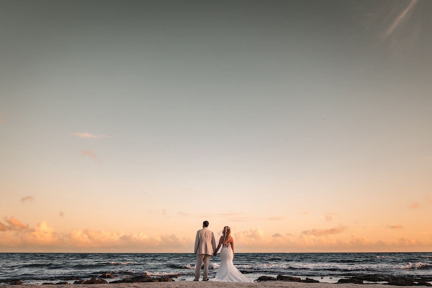 Romantic beach wedding photography during a pastel sunset with ocean views.