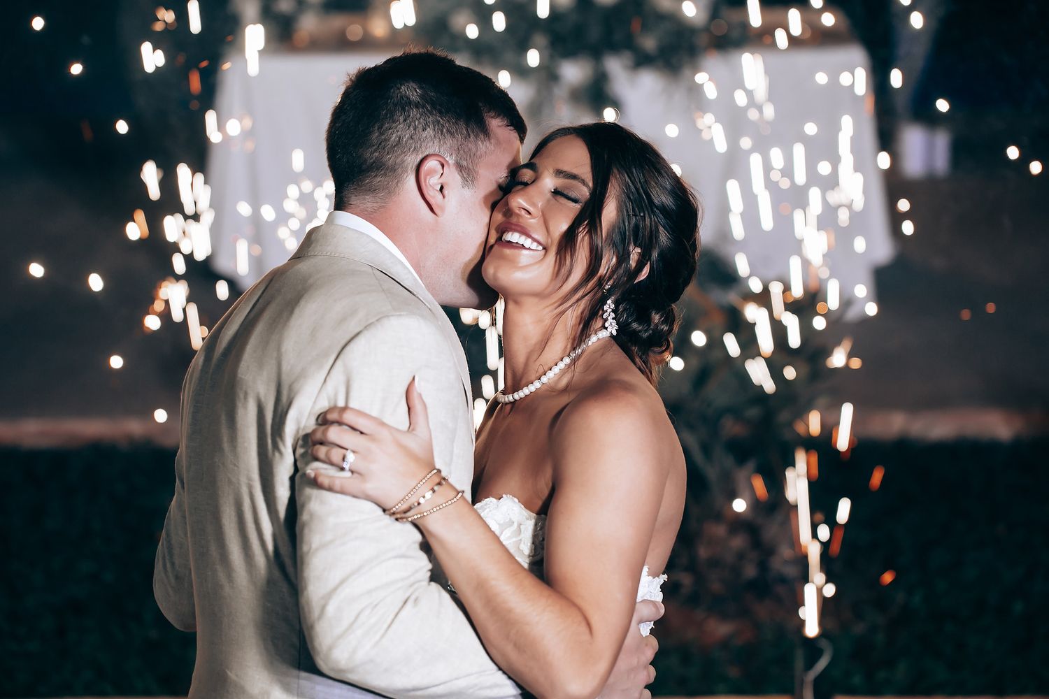 Romantic first dance with sparklers creating magical lighting effects in the background.