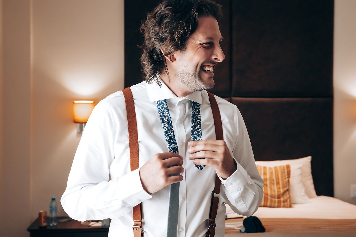 Two people in white shirts and ties share a joyful moment while sitting indoors.