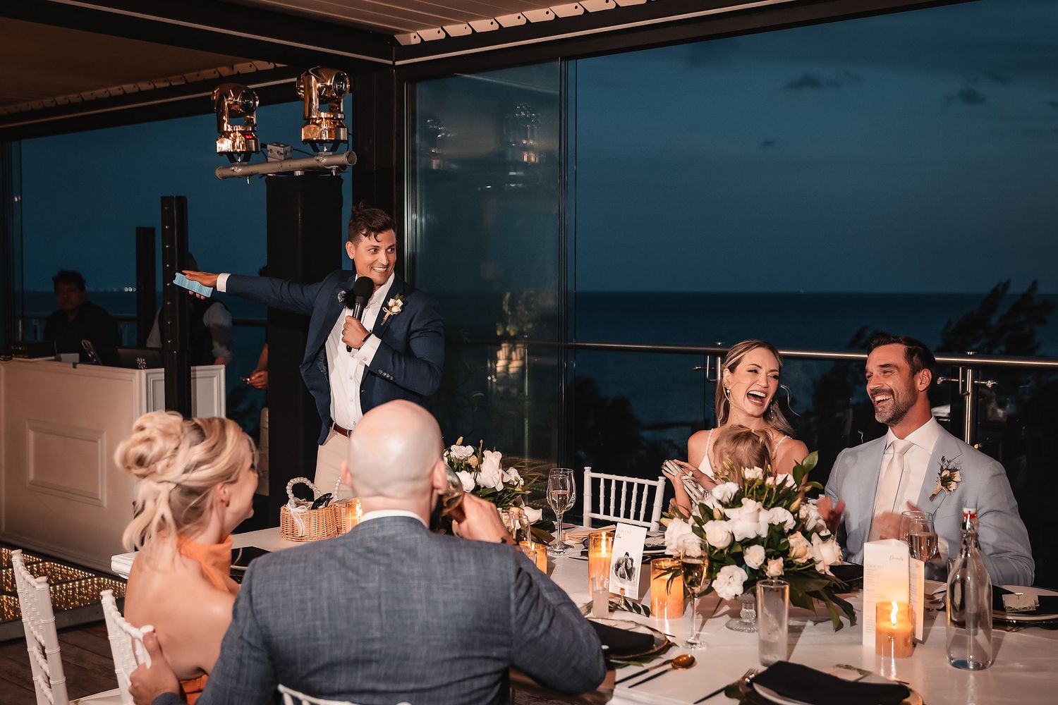 Wedding toast speech during sunset at elegant outdoor reception with candlelit table settings.