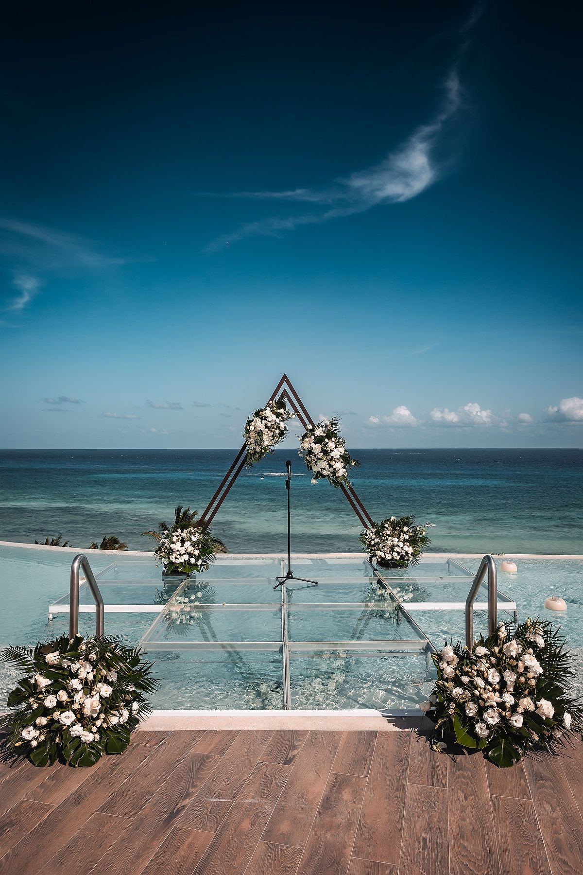 Wooden deck wedding altar decorated with white floral arrangements overlooking the ocean.