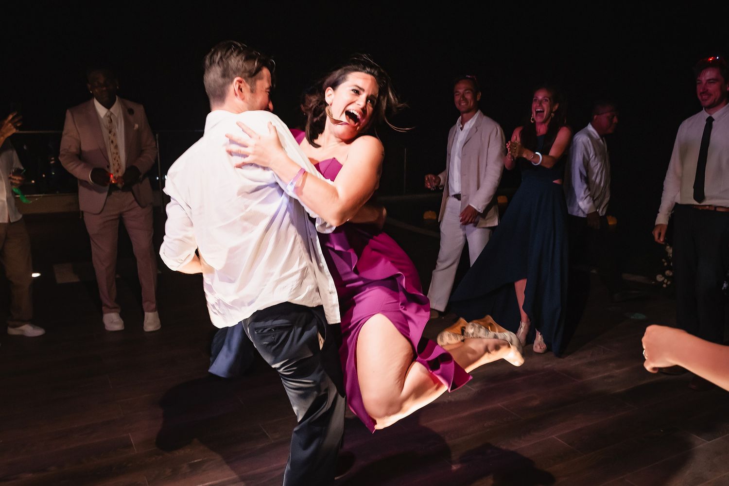 Couples dancing together at an evening social event with dramatic lighting.