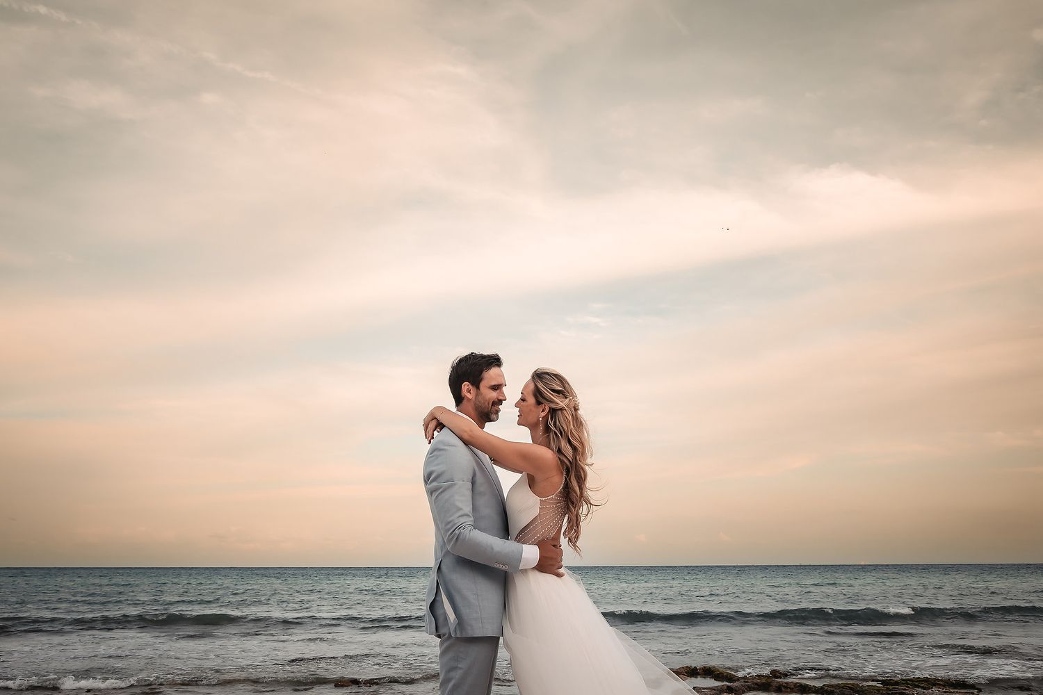 Dreamy beach wedding portraits with soft sunset lighting and ocean backdrop.
