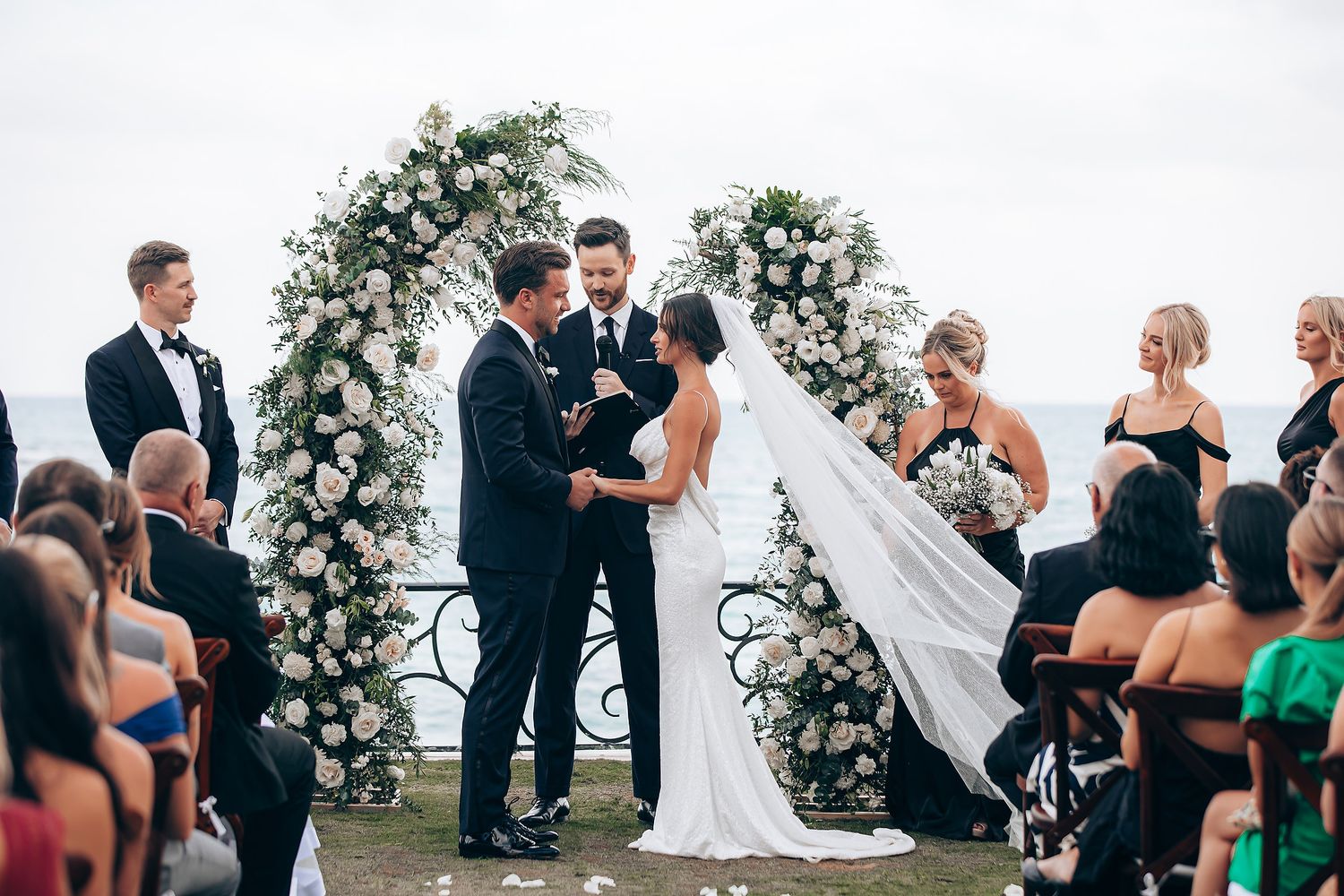 Wedding ceremony guests gather outdoors under a cloudy sky during an intimate celebration.