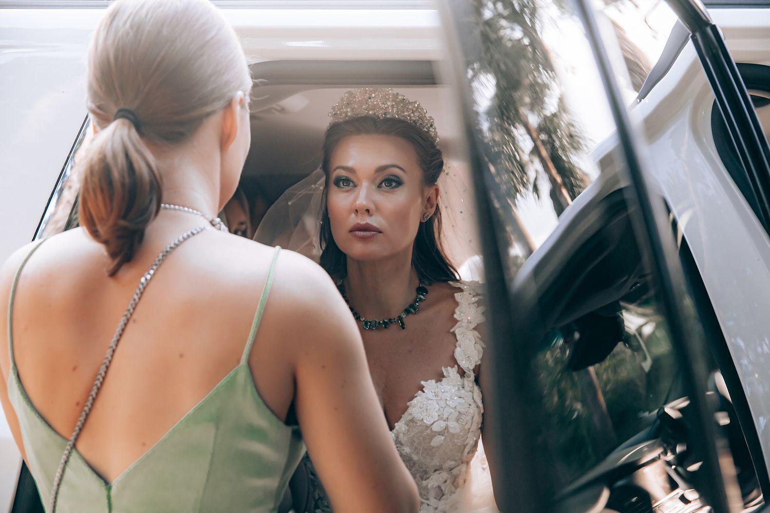 A group of people getting ready in a dressing room with makeup and styling tools visible in the mirror reflections.