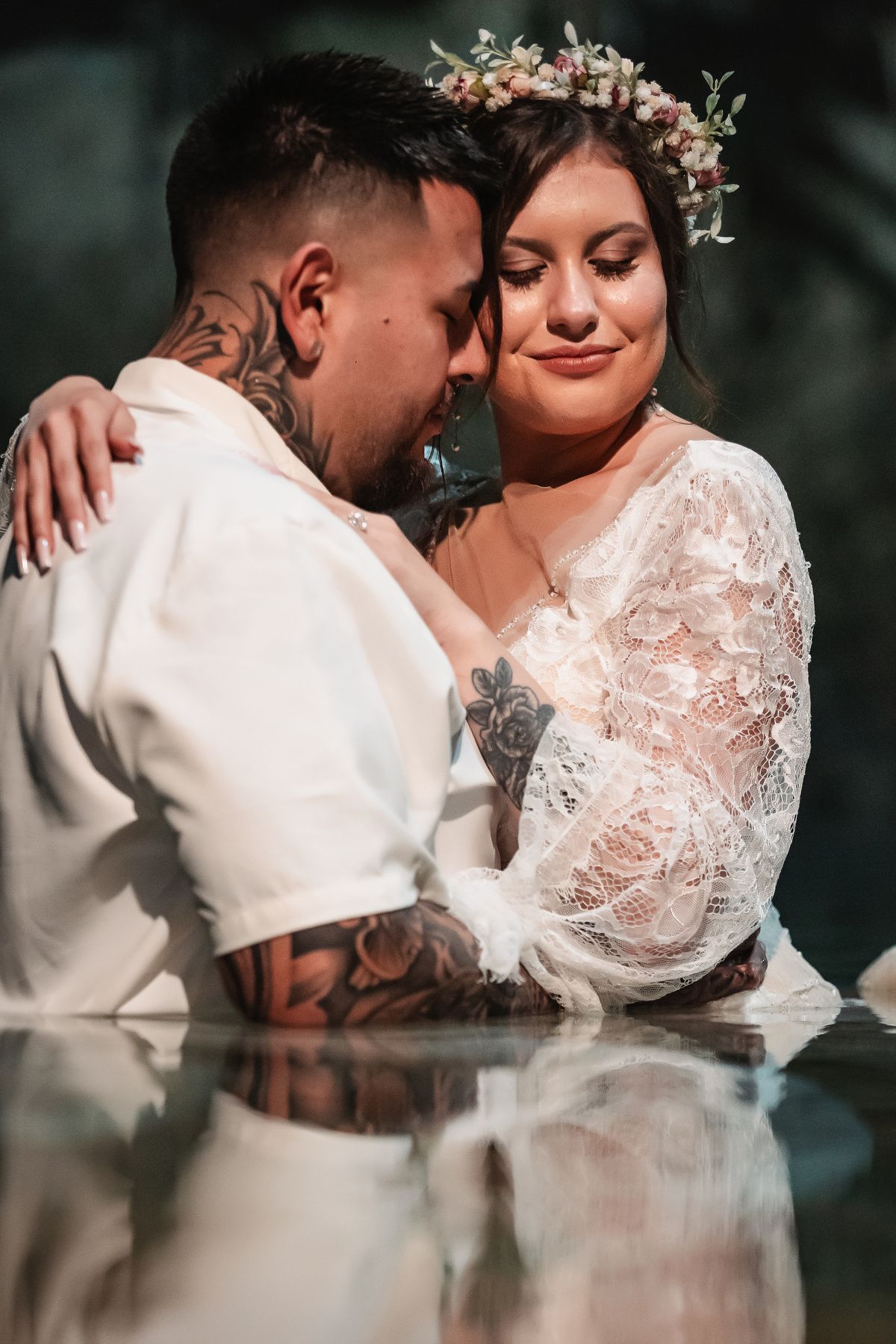 An intimate portrait of newlyweds sharing a close embrace in white wedding attire.