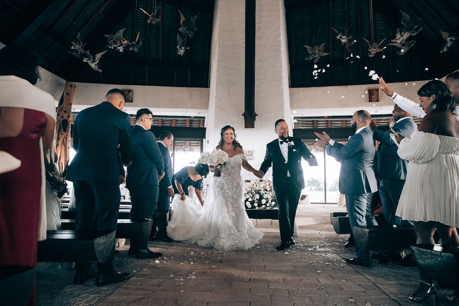 Wedding reception celebration with guests dancing in a spacious venue with high wooden beams.