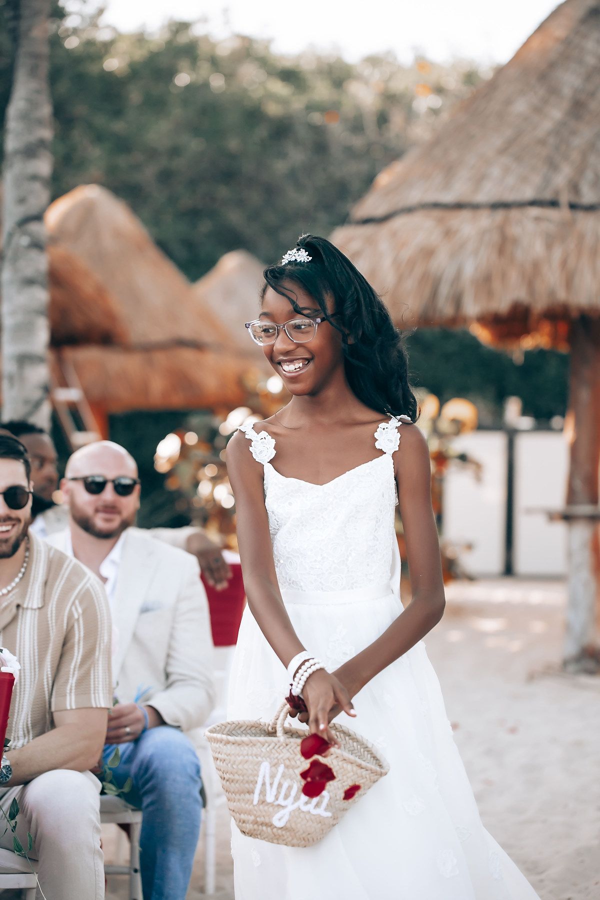 Wedding guests enjoying a beachside celebration with thatched roof huts and tropical decor.
