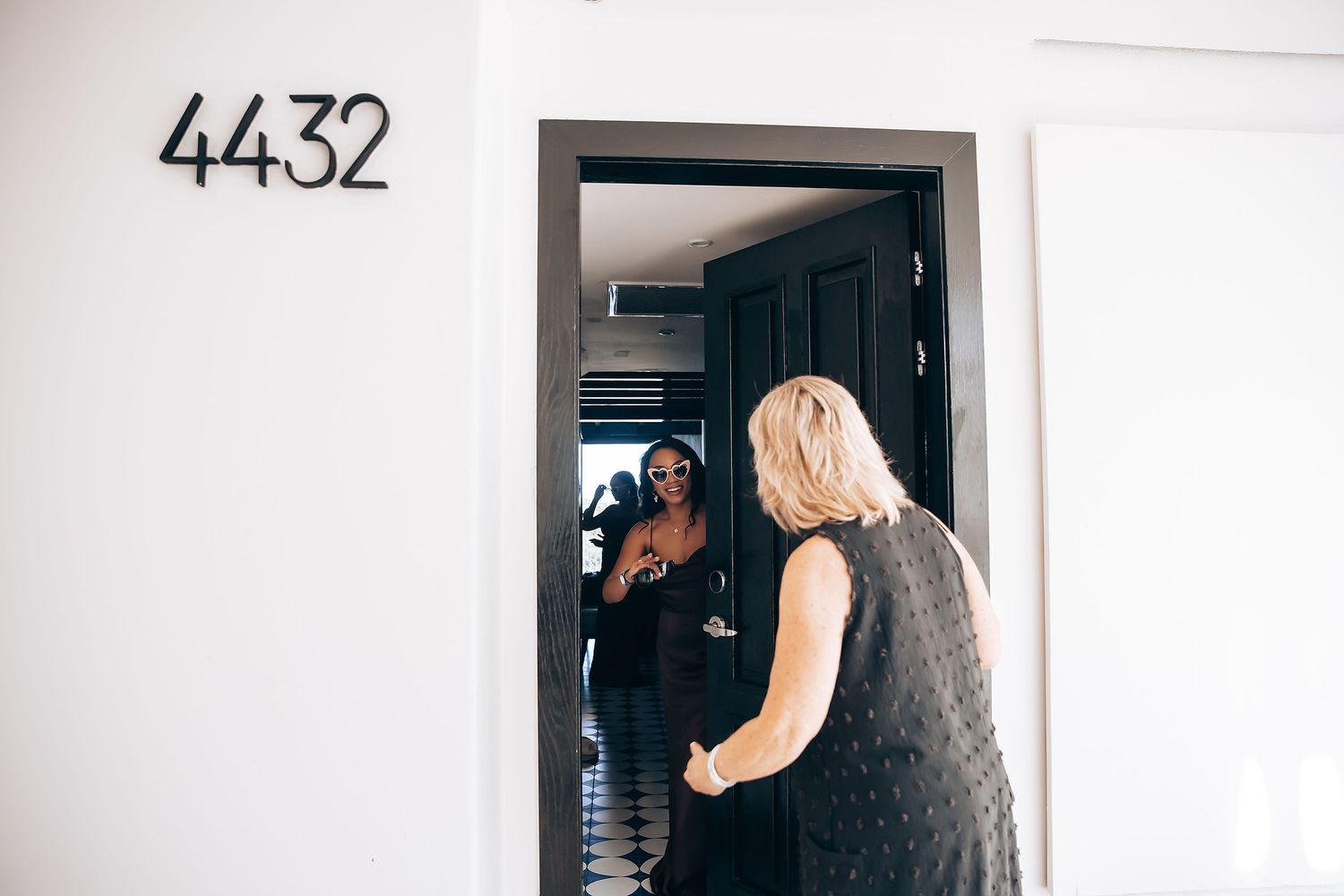 Two people stand in a doorway marked with number 4432 in a bright interior hallway.