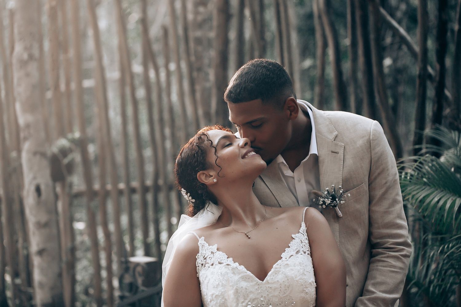 Newlyweds share tender moments against a backdrop of trees in a natural forest setting.
