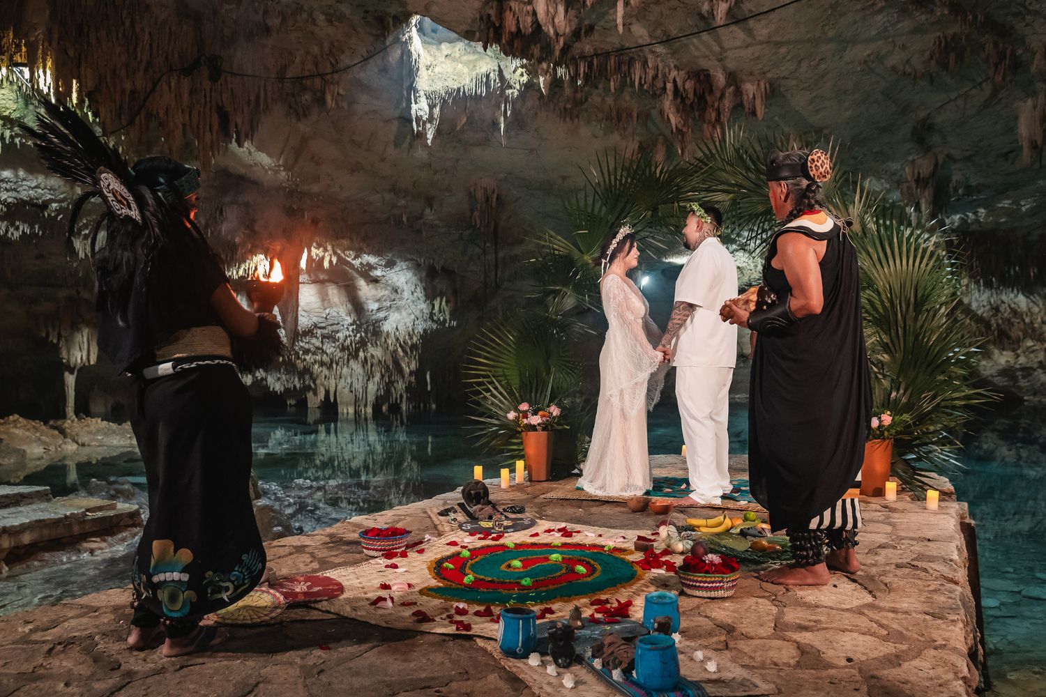 Romantic cave wedding ceremony with candlelit decorations and turquoise water backdrop.