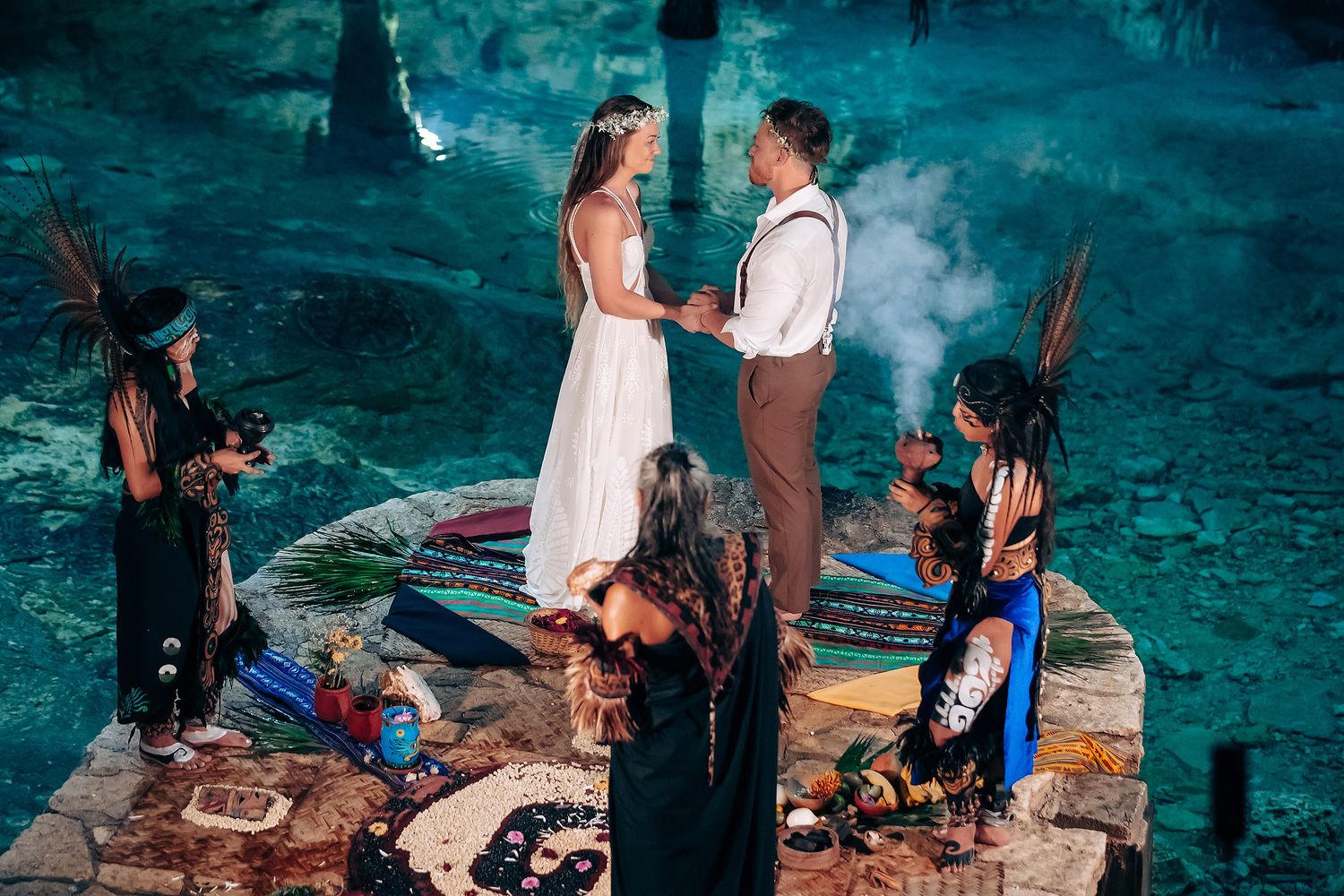 An intimate gathering in a dimly lit cave with turquoise water and natural rock formations.