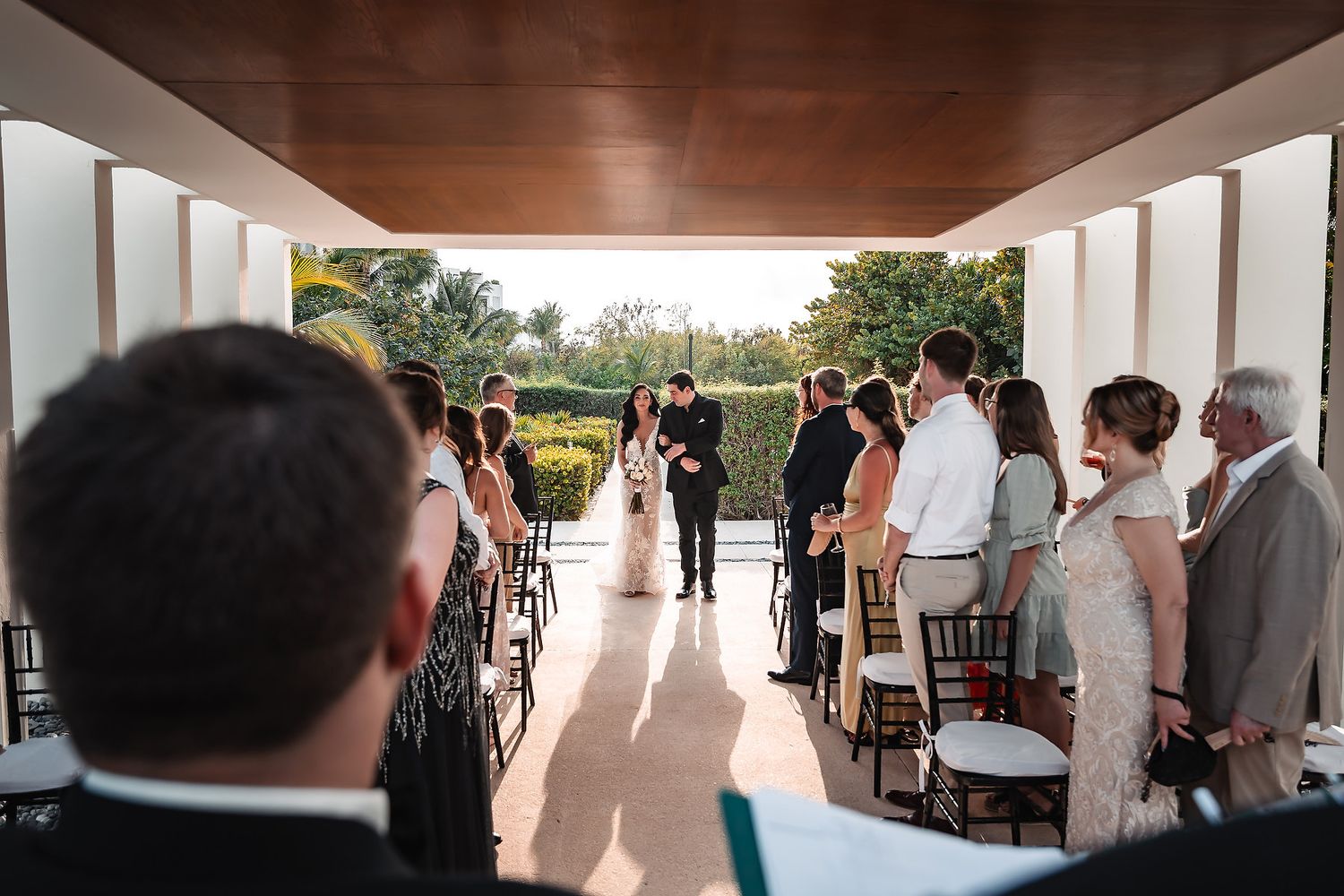 Modern wedding venue with white pillars and wooden ceiling features natural light streaming through windows.