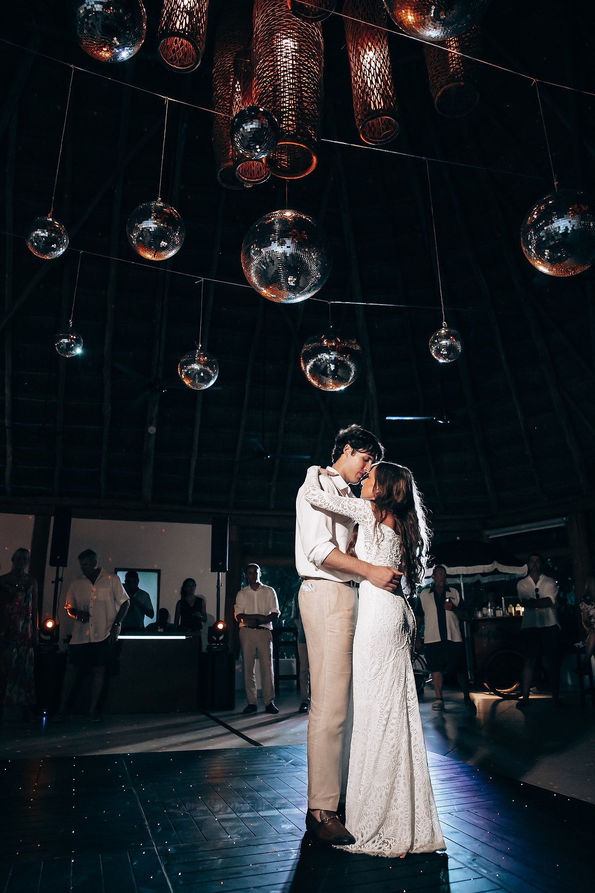 Wedding dance under hanging disco balls in a dimly lit reception venue.