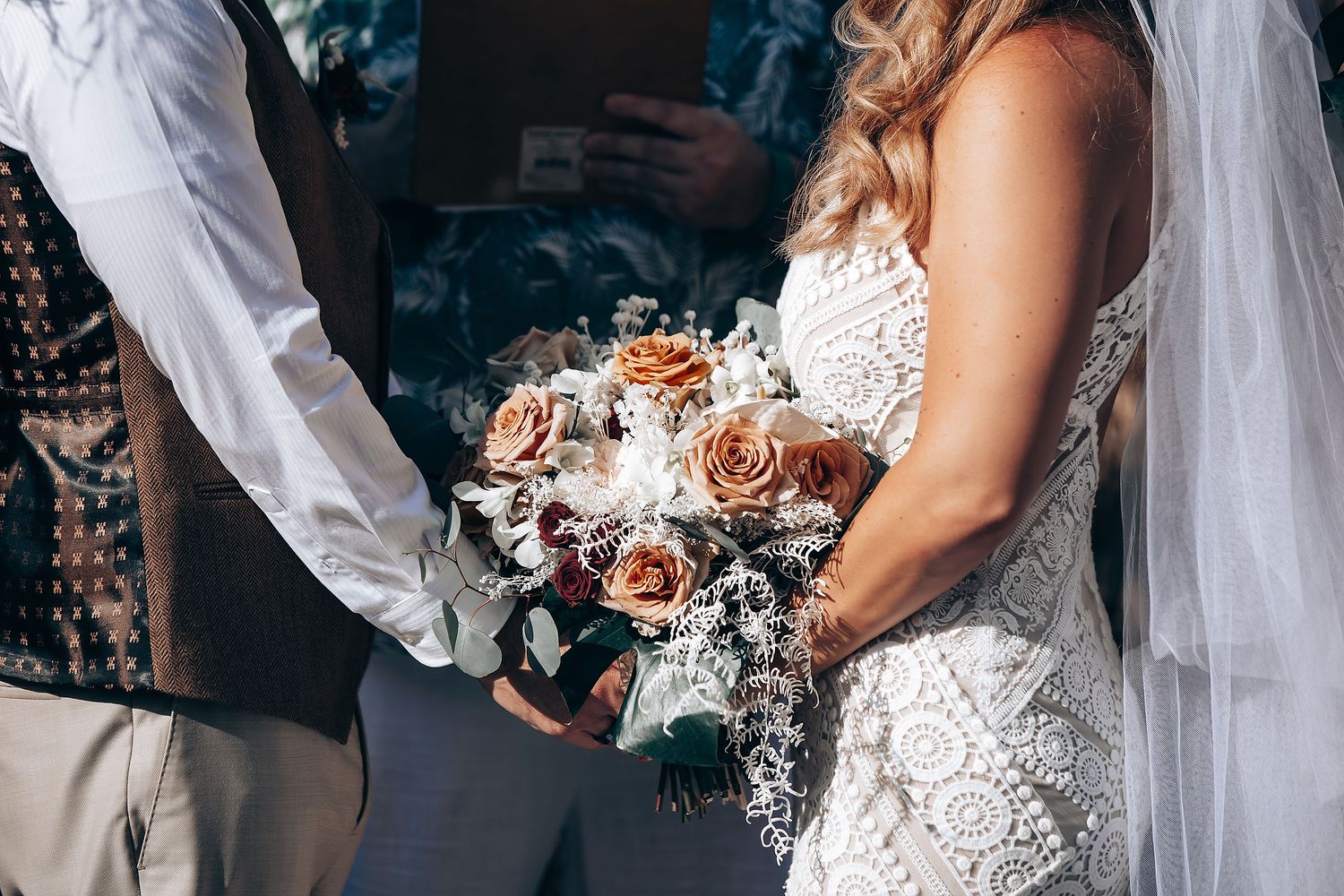 Close-up details of white lace wedding dress with intricate embroidery patterns.