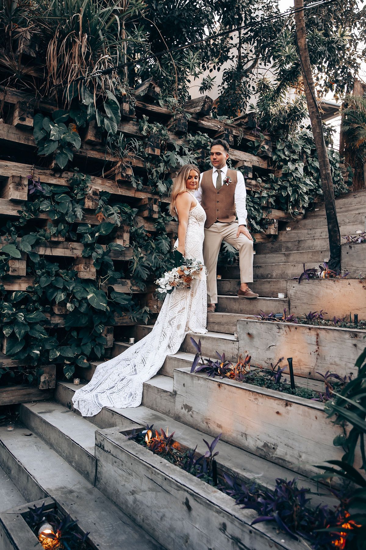 Romantic wedding photoshoot on rustic garden steps with natural foliage backdrop.