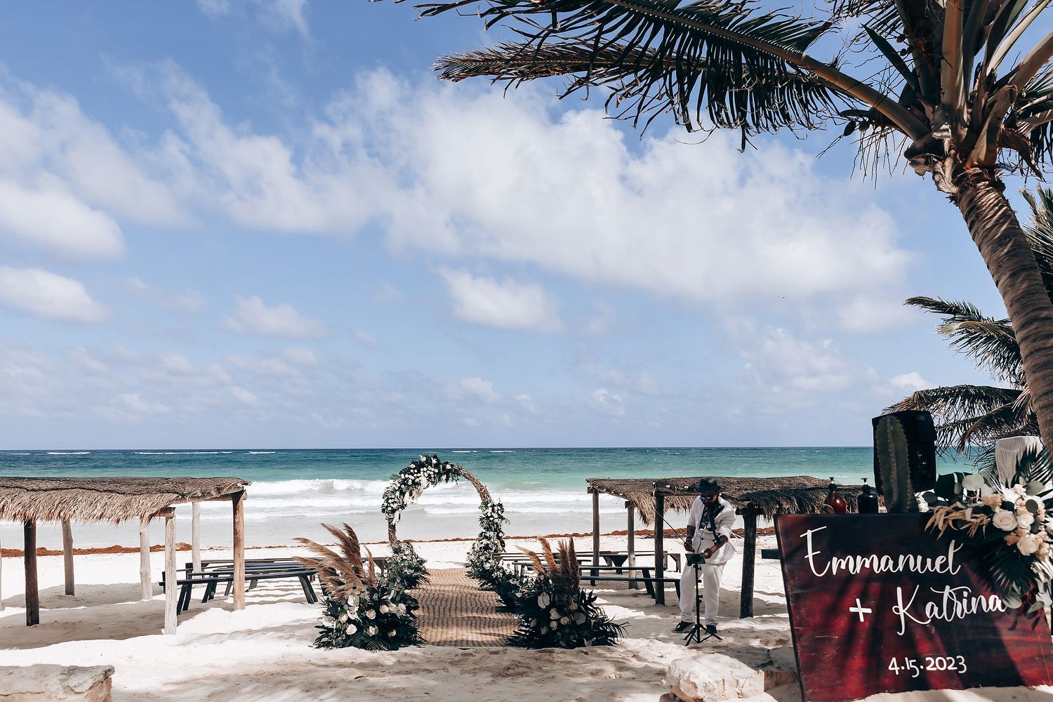 Wide angle view of a beach wedding venue with decorated arch and seating arrangements.