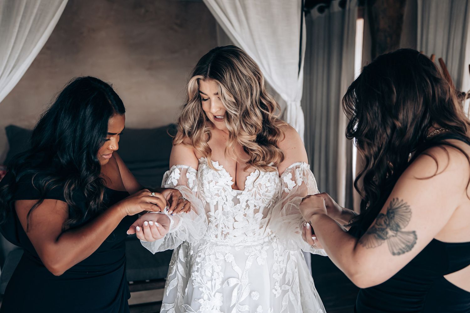 Multiple angles showing the detailed back of a white lace wedding gown being fastened.