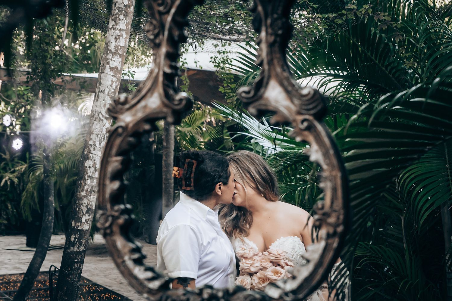 Wedding venue decorated with hanging circular mirrors reflecting natural light through palm trees.