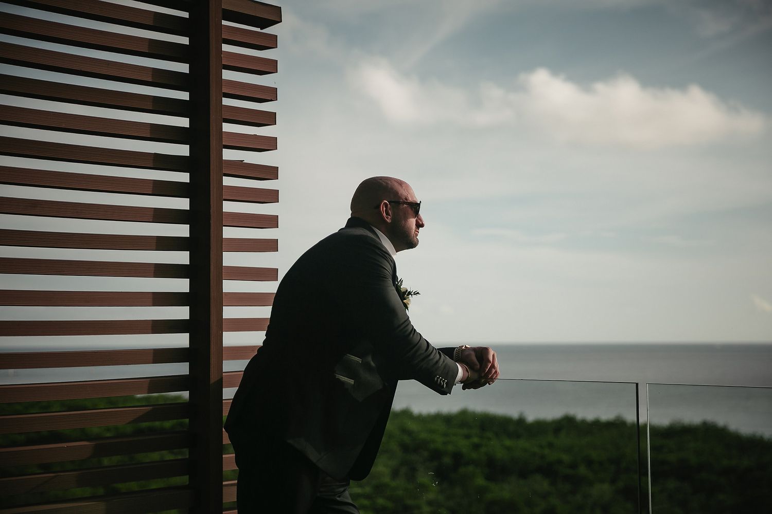 Silhouette of photographer capturing shots against cloudy coastal backdrop.
