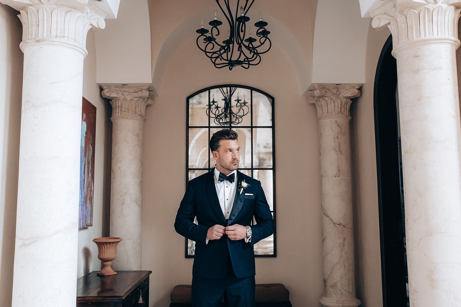 Classic formal portrait in an elegant venue with white columns and arched windows.