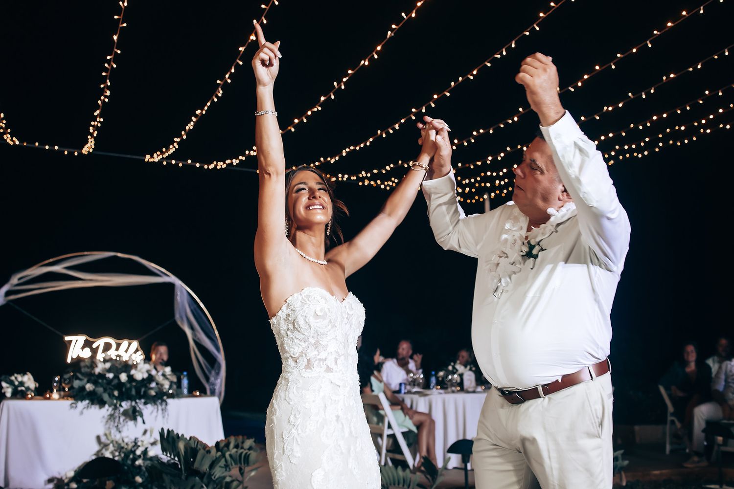 Wedding reception dance under twinkling string lights at night.