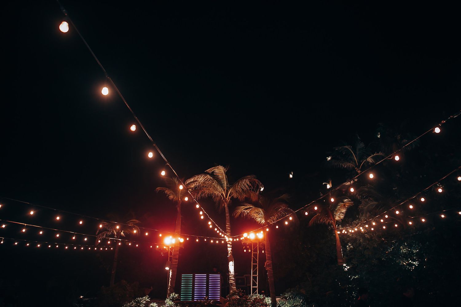 String lights illuminate a dark outdoor wedding venue creating a romantic ambiance.