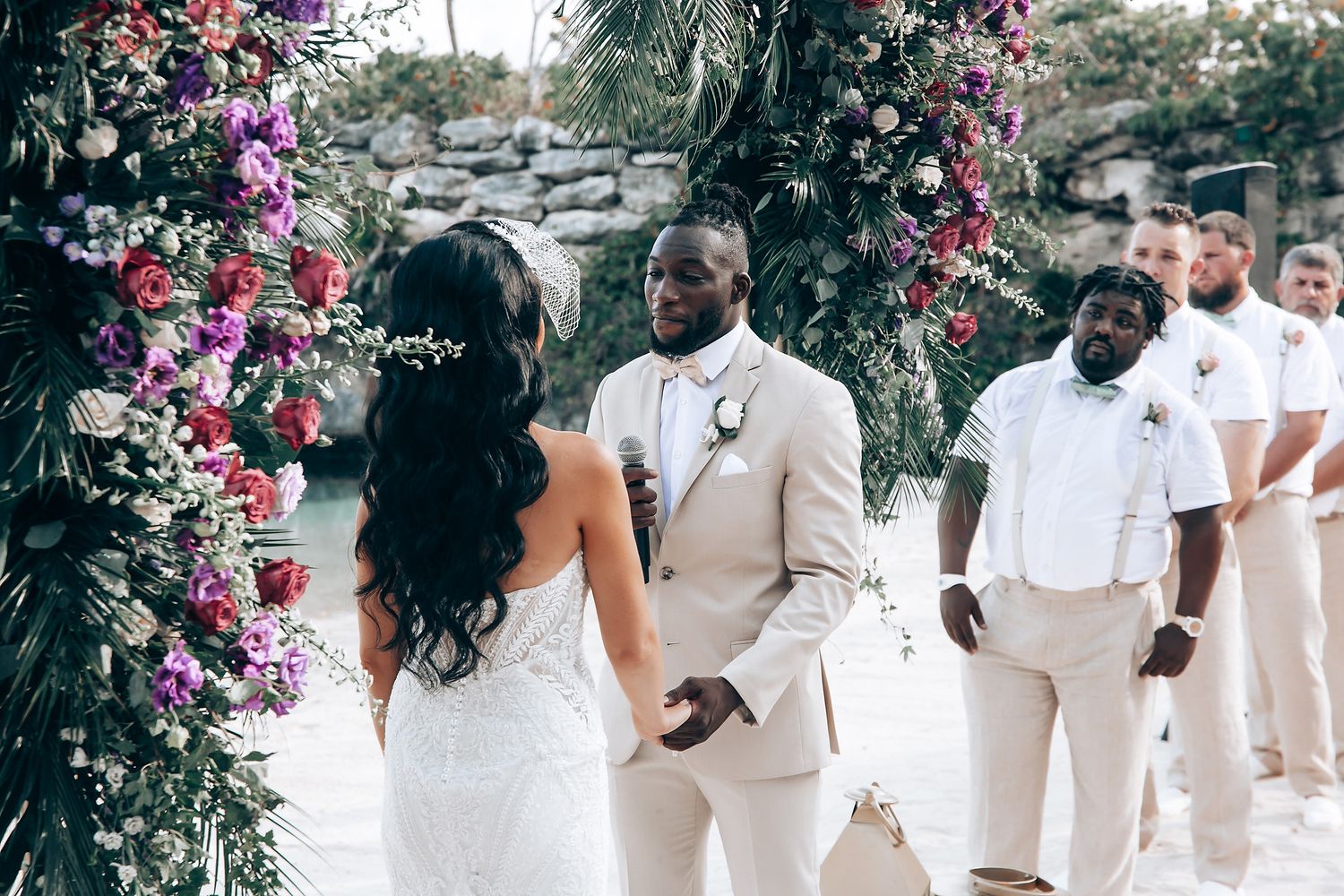 Wedding ceremony in progress under an arch decorated with vibrant pink flowers.