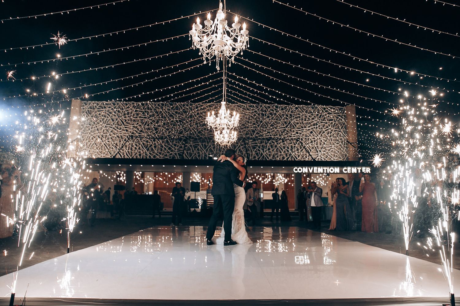 A grand wedding reception venue with crystal chandeliers and sparkling string lights creating a magical ambiance.