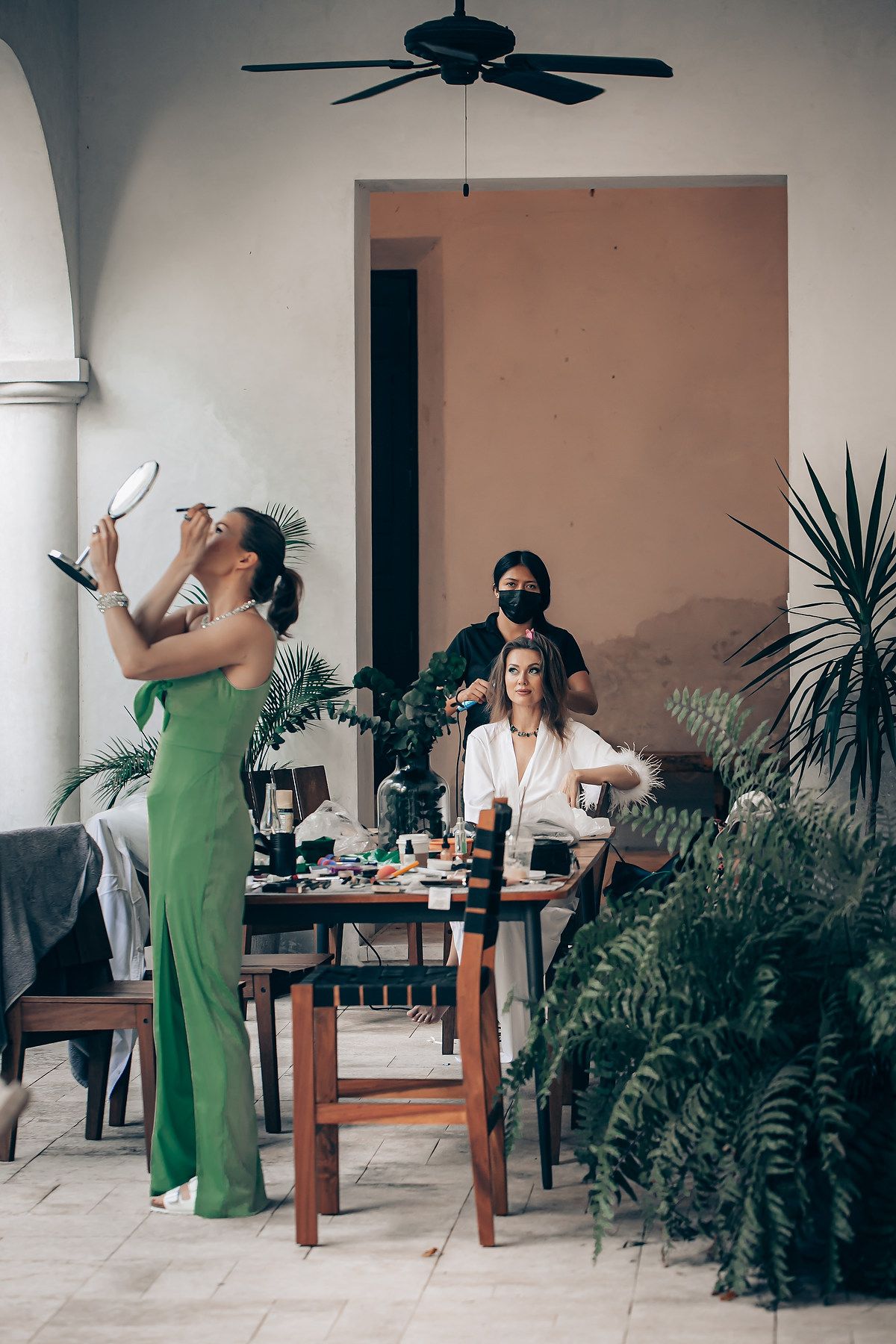 A sequence of photos showing someone in a green dress dancing and moving around a tropical indoor space with plants.