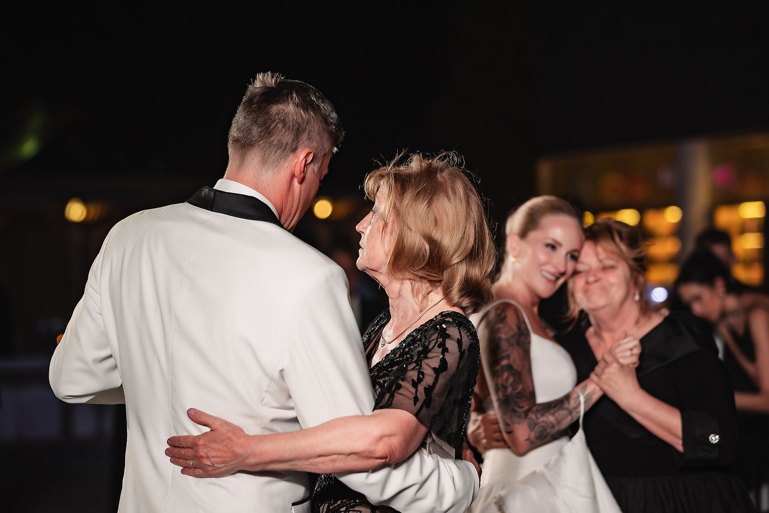 Couples dancing together during an evening wedding reception with ambient lighting.
