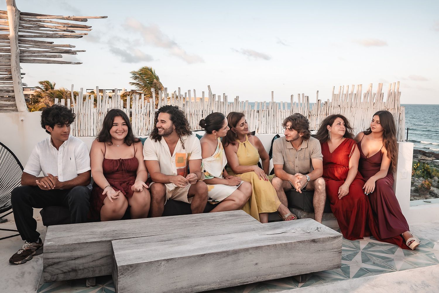 Group relaxing on a beachfront wall at sunset with ocean views.