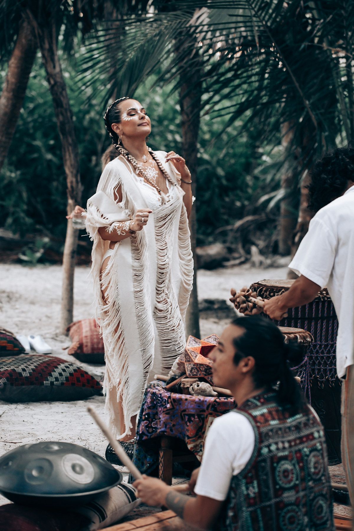 Beach celebration with musical instruments and people in white bohemian attire.
