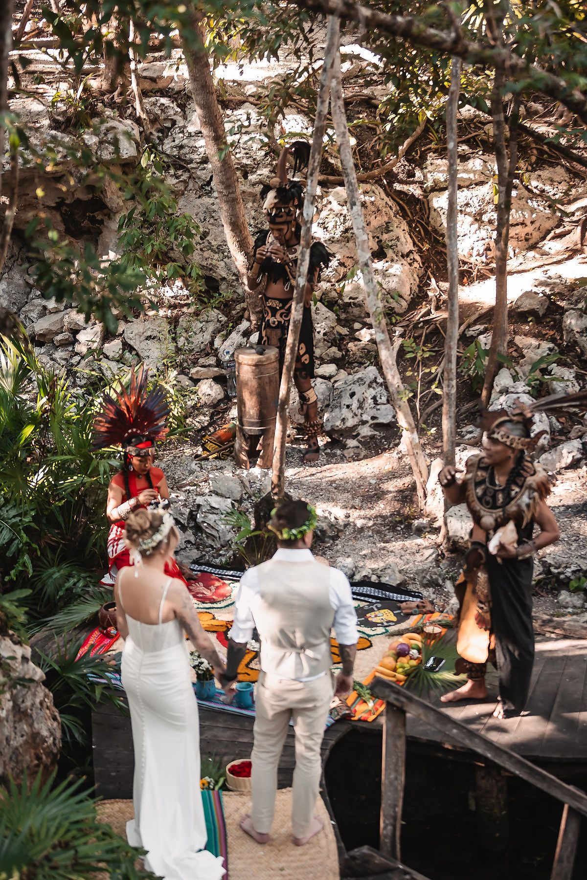 Traditional Mayan ceremony being performed in a natural cenote setting with ceremonial decorations and offerings.