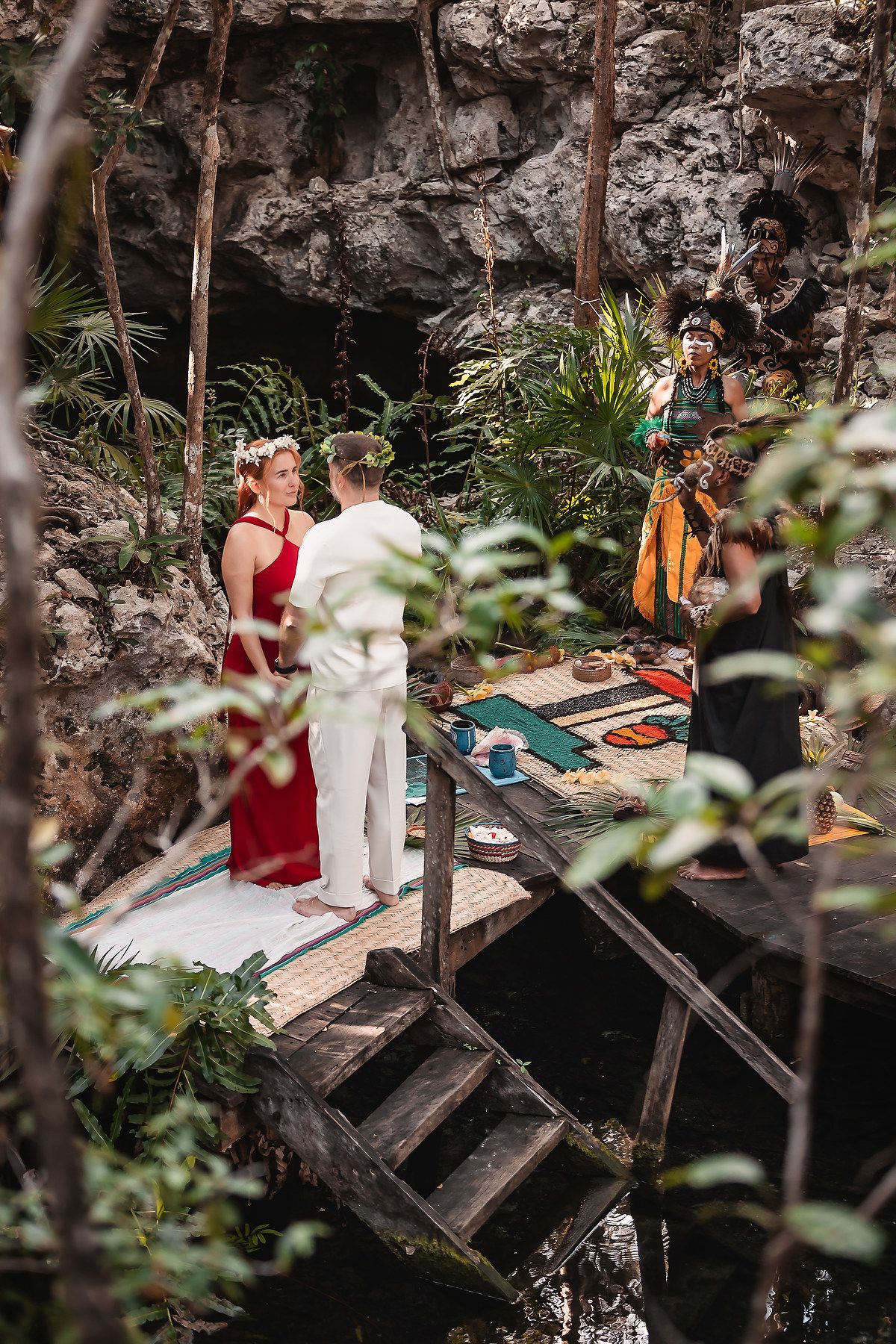 A ceremony takes place on wooden platforms in a scenic cave setting with natural light.