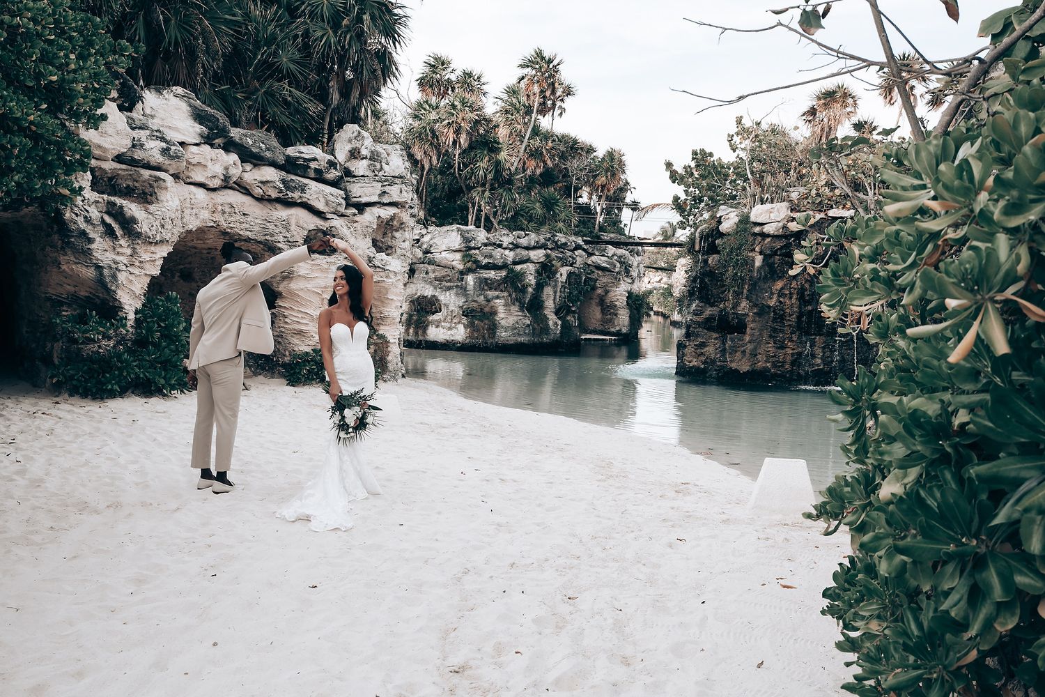 Wedding ceremony setup on tropical beach with stone pathway and greenery.